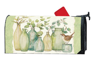 MailWrap with 6 different shaped vases full of eucalyptus branches and one little brown bird atop the smallest vase